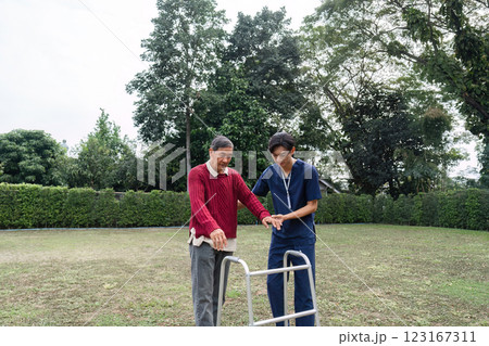 Dedicated caregiver supporting elderly man with walker in sunny garden, enhancing mobility and trust Dedicated caregiver supporting elderly man with walker in sunny garden, enhancing mobility and trust 123167311