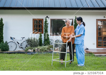 Elderly Woman with Caregiver Walking in Garden Outside Home, Enjoying Fresh Air and Nature, Senior Care and Support Concept Elderly Woman with Caregiver Walking in Garden Outside Home, Enjoying Fresh Air and Nature, Senior Care and Support Concept 123167314