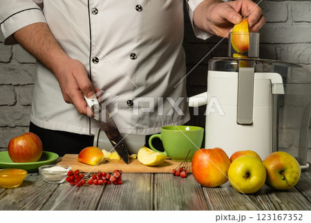 Crafting delicious apple juice, a skilled chef slices vibrant apples while preparing to extract their sweet essence. The kitchen ambiance is warm and inviting, filled with fresh produce 123167352