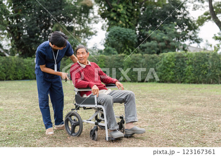 Nursing aide engaging with elderly man in wheelchair, encouraging conversation in tranquil garden 123167361