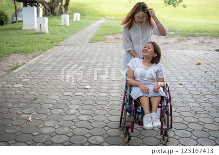 Young Woman in Wheelchair Enjoying a Walk in the Park with Her Best Friend on a Sunny Day 123167413