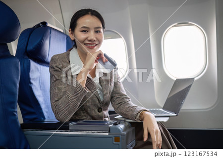 Young Asian woman holding credit card shopping online using website on laptop Sitting near window in first class on airplane during flight, travel and business concept. Young Asian woman holding credit card shopping online using website on laptop Sitting near window in first class on airplane during flight, travel and business concept. 123167534