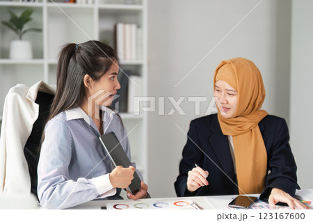 Diverse female finance professionals discussing strategies in a modern office setting. 123167600