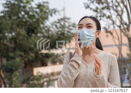 Young woman smiling while wearing a mask outdoors, addressing pollution concerns. Young woman smiling while wearing a mask outdoors, addressing pollution concerns. 123167617
