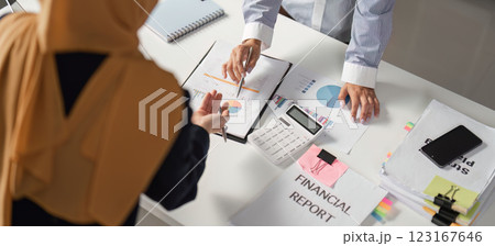 Diverse female finance professionals discussing financial reports in an office setting. 123167646