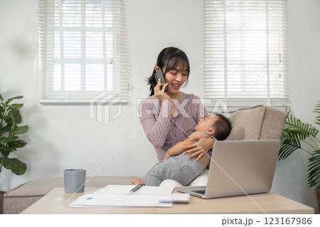 Joyful mother engaging on a phone call while holding her baby at home Joyful mother engaging on a phone call while holding her baby at home 123167986