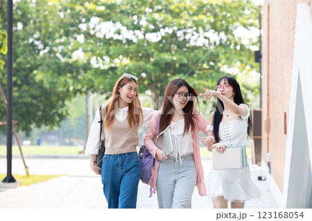Happy Asian teenager female college student holding book and looking at nature outdoors at university Prepare for class 123168054