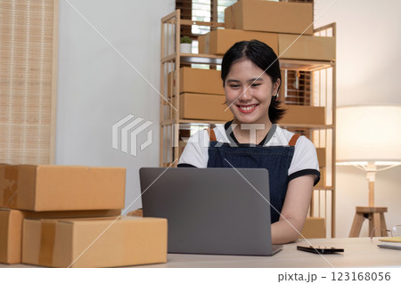 young female entrepreneur writes on the front of a product box to sell products online and prepares to send them to customers. Online selling at home, working from home 123168056