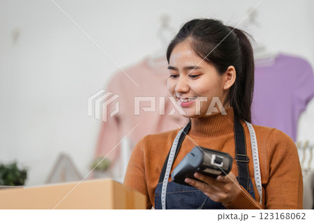 Diverse young woman smiling while scanning packages in a fashion retail store. Diverse young woman smiling while scanning packages in a fashion retail store. 123168062