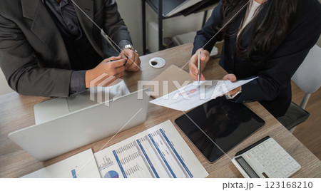 Business professionals analyzing financial documents and data on a desk in a modern office. Business professionals analyzing financial documents and data on a desk in a modern office. 123168210