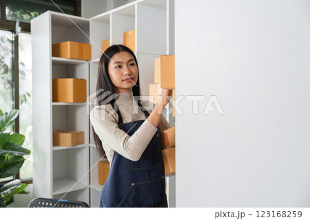 E-commerce businesswoman organizing packages on a shelf in a modern office environment. 123168259
