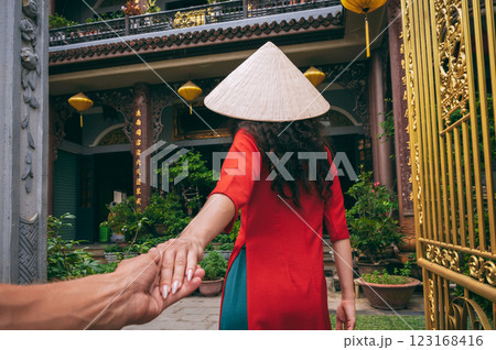 Follow me with back of a female traveler tourist in Vietnamese hat at a temple in Vietnam in Asia. The concept of travel in Asia 123168416