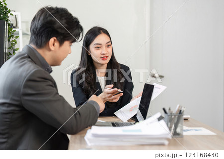 Business professionals discussing financial reports and strategies in a modern office setting. 123168430