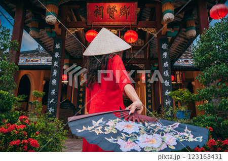 Back of a female tourist traveler in a Vietnamese hat Non La with fan at Buddhist temple in Hoi An in Vietnam in Asia 123168431