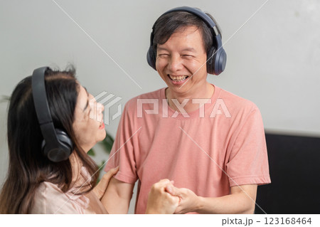 Mature couple sharing laughter and dancing with headphones at home. 123168464