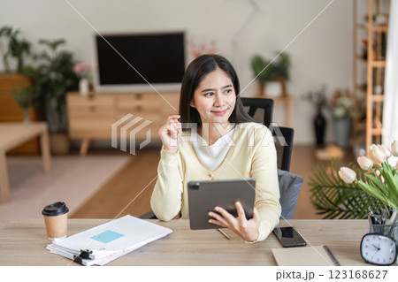 Thoughtful woman using a tablet in her home office, contemplating ideas 123168627