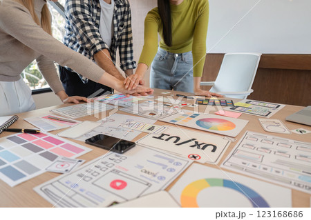 Diverse team collaborating on UX design project, celebrating creativity and teamwork at a modern workspace. 123168686