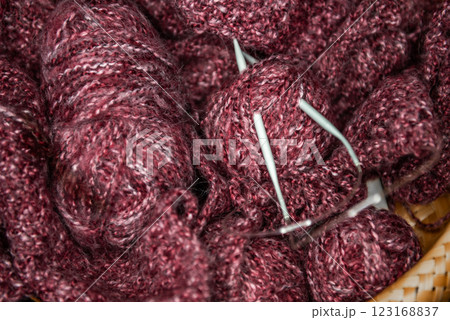 yarns, knitting needles and pattern sample in basket on sofa. 123168837