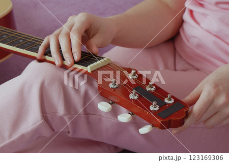 Woman's hands tuning guitar. Hand moves methodically tightening and loosening strings before playing Woman's hands tuning guitar. Hand moves methodically tightening and loosening strings before playing 123169306