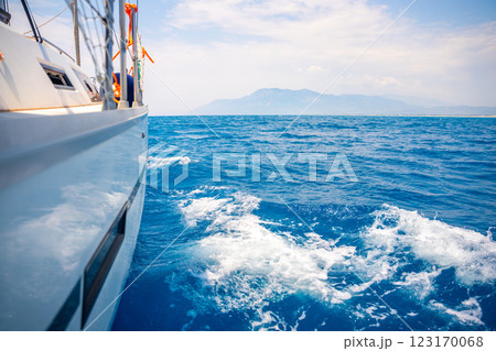 Yacht sailing in an open sea. Close-up view of side of the boat. Clear sky after the rain, waves and water splashes 123170068