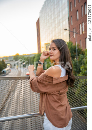 Attractive young woman enjoying her free time at sunset outdoor. Happy girl portrait at summer. Freedom lifestyle summer concept. Sun glow on background. Attractive young woman enjoying her free time at sunset outdoor. Happy girl portrait at summer. Freedom lifestyle summer concept. Sun glow on background. 123170091
