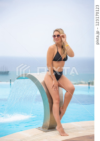 Portrait of beautiful woman in swimwear relaxing in swimming pool in resort 123170123