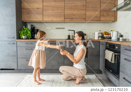 Little girl giving bouquet of flowers and drawing to her mum on the home kitchen. Mothers day, birthday or International Women's Day 8 march concept 123170210