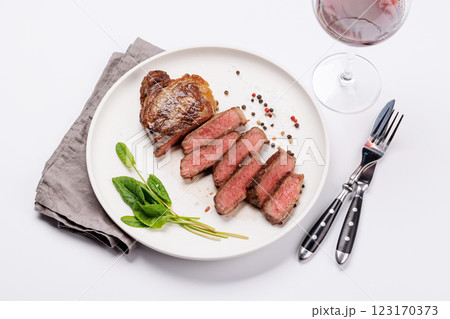 A perfectly cooked sliced striploin steak with a juicy, tender texture, served alongside a glass of rich red wine A perfectly cooked sliced striploin steak with a juicy, tender texture, served alongside a glass of rich red wine 123170373