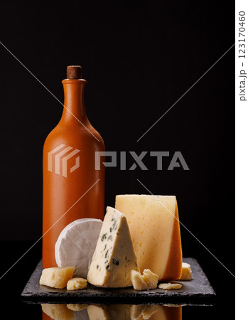 A refined selection of aged cheeses presented on a board, accompanied by a bottle of wine 123170460