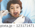 Cute arab boy sitting at dental chair with open mouth during oral checking up with doctor. Visiting sunny dentist office 123171471