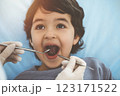 Cute arab boy sitting at dental chair with open mouth during oral checking up with doctor. Visiting sunny dentist office 123171522