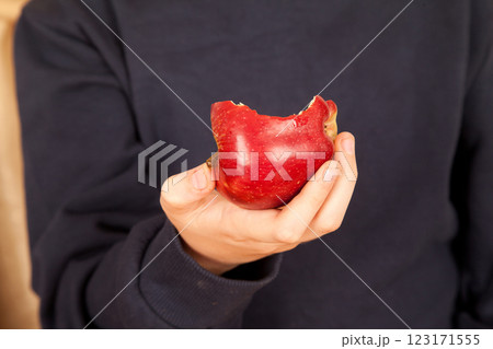 Young Caucasian male in navy blue t-shirt holding a bitten fresh red apple 123171555