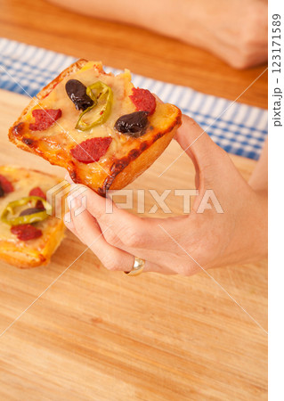 Caucasian white person holding pizza pieces on bamboo cutting board on blue napkin 123171589