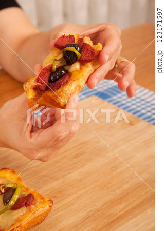 Caucasian white person holding pizza pieces on bamboo cutting board on blue napkin Caucasian white person holding pizza pieces on bamboo cutting board on blue napkin 123171597