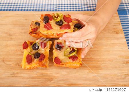 Caucasian white person holding pizza pieces on bamboo cutting board on blue napkin 123171607
