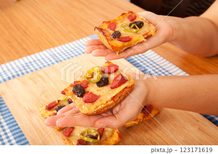Caucasian white person holding pizza pieces on bamboo cutting board on blue napkin 123171619