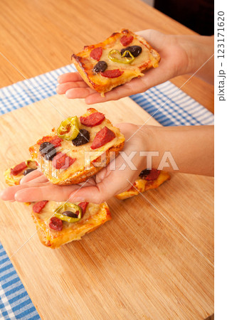 Caucasian white person holding pizza pieces on bamboo cutting board on blue napkin 123171620