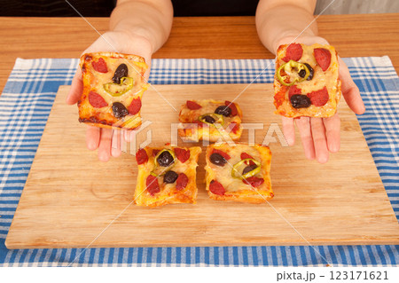 Caucasian white person holding pizza pieces on bamboo cutting board on blue napkin 123171621