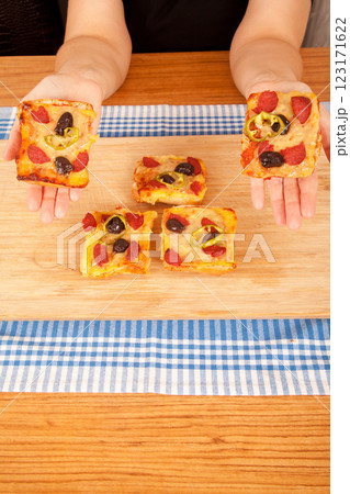 Caucasian white person holding pizza pieces on bamboo cutting board on blue napkin 123171622