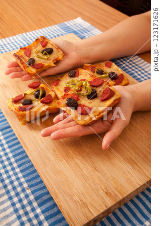 Caucasian white person holding pizza pieces on bamboo cutting board on blue napkin 123171626