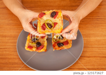 Caucasian white person holding delicious pizza slices in grey plate on wooden table Caucasian white person holding delicious pizza slices in grey plate on wooden table 123171627