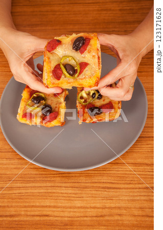 Caucasian white person holding delicious pizza slices in grey plate on wooden table Caucasian white person holding delicious pizza slices in grey plate on wooden table 123171628