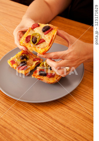 Caucasian white person holding delicious pizza slices in grey plate on wooden table Caucasian white person holding delicious pizza slices in grey plate on wooden table 123171629