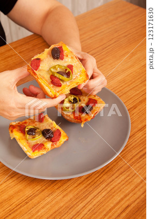 Caucasian white person holding delicious pizza slices in grey plate on wooden table 123171630