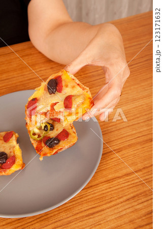 Caucasian white person holding delicious pizza slices in grey plate on wooden table Caucasian white person holding delicious pizza slices in grey plate on wooden table 123171632