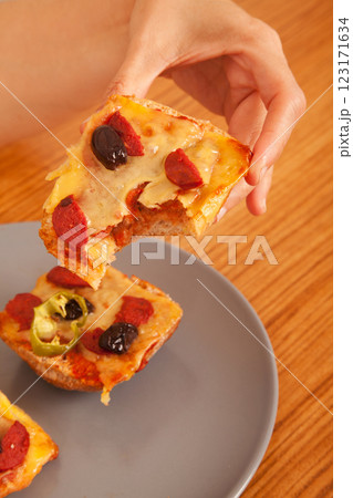 Caucasian white person holding delicious pizza slices in grey plate on wooden table 123171634