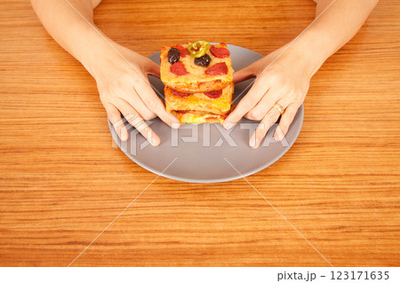 Caucasian white person holding delicious pizza slices in grey plate on wooden table Caucasian white person holding delicious pizza slices in grey plate on wooden table 123171635