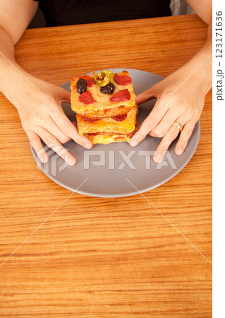 Caucasian white person holding delicious pizza slices in grey plate on wooden table Caucasian white person holding delicious pizza slices in grey plate on wooden table 123171636