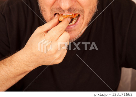 Bearded Caucasian white mature male in black t-shirt eating delicious pizza slices 123171662
