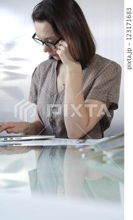 Focused businesswoman in brawn dotted blouse is using laptop and thinking with hand on chin, working on a project in a bright office. Business people concept Focused businesswoman in brawn dotted blouse is using laptop and thinking with hand on chin, working on a project in a bright office. Business people concept 123171683